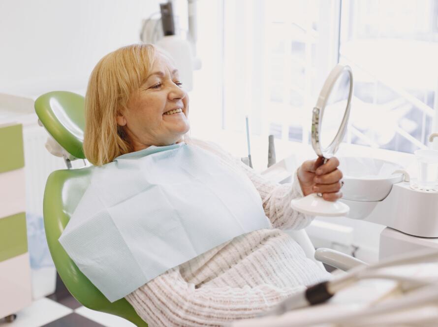 Mujer sentada en el sillón dental mirándose en un espejo